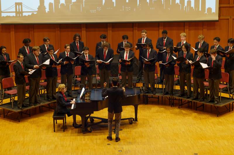 a group of people standing on stage with a piano and a man standing in front of him