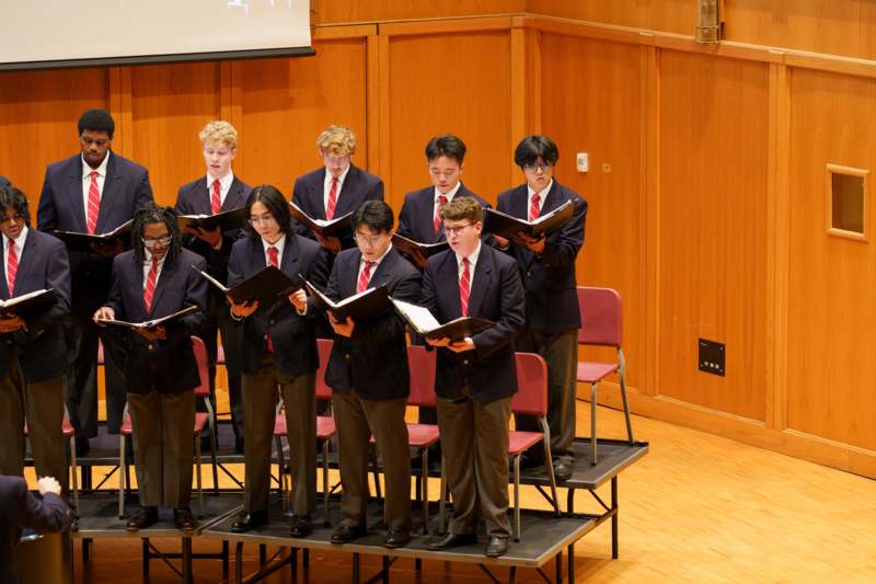a group of people in suits singing on a stage