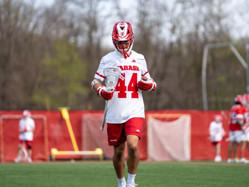 a man wearing a helmet and holding a lacrosse stick