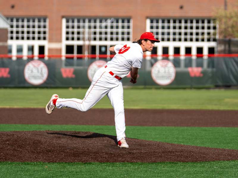a baseball player in a red hat throwing a ball