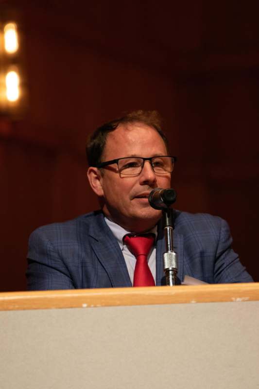 a man in a suit and tie speaking into a microphone