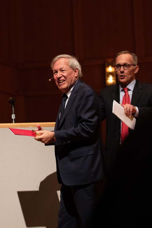 a man in suit and tie holding a red envelope
