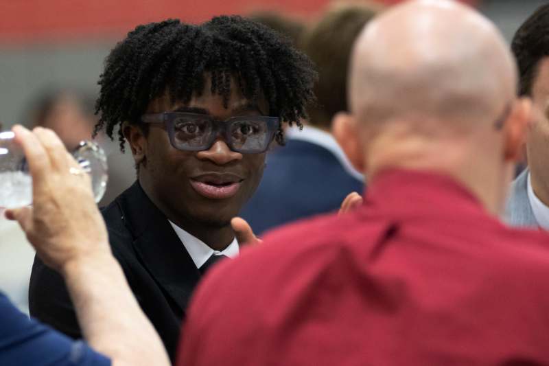 a man in a suit and tie talking to another man
