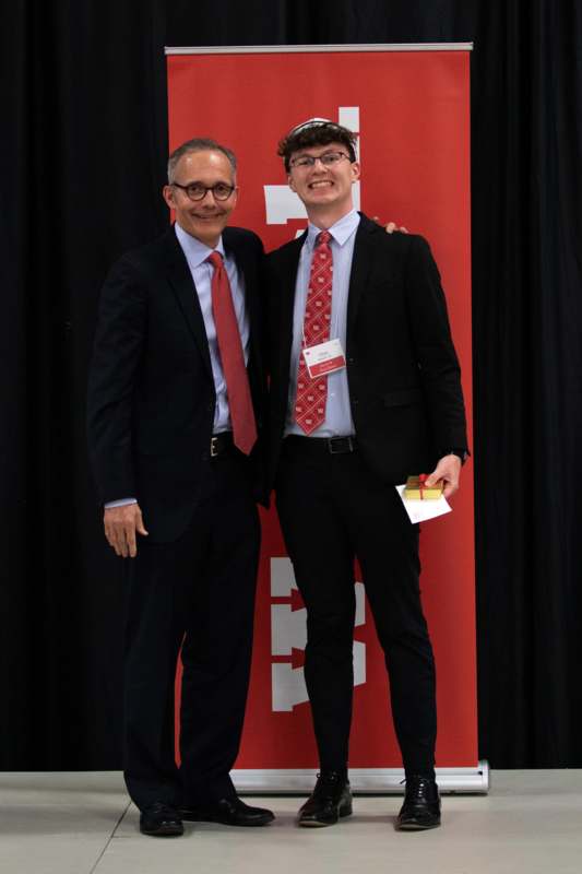 two men standing in front of a red and black backdrop