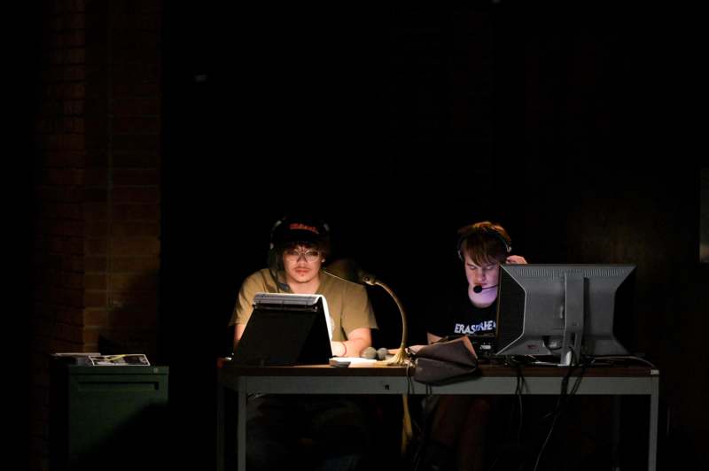 a group of men sitting at a desk with computers and microphones