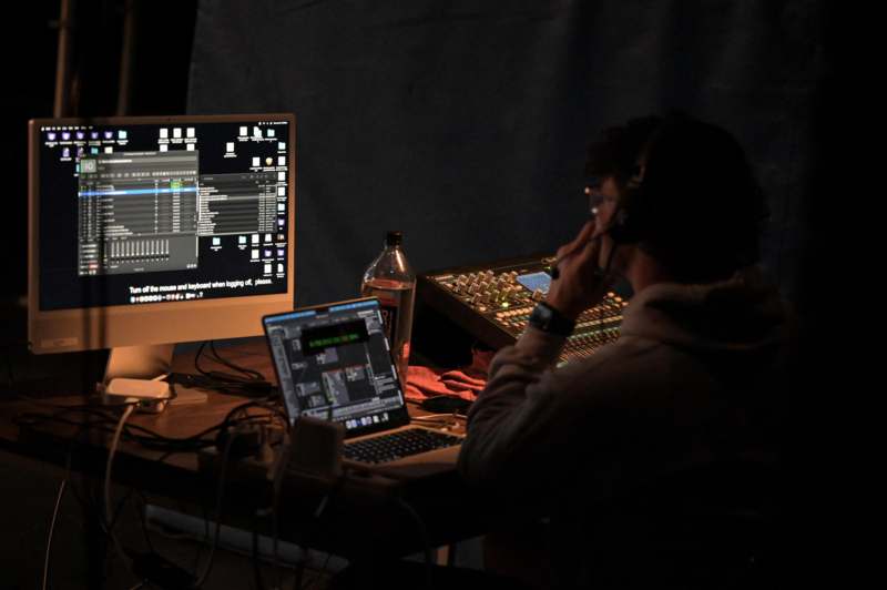 a man sitting at a desk with a computer and a microphone