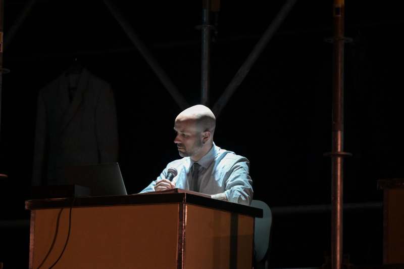 a man sitting at a podium with a microphone