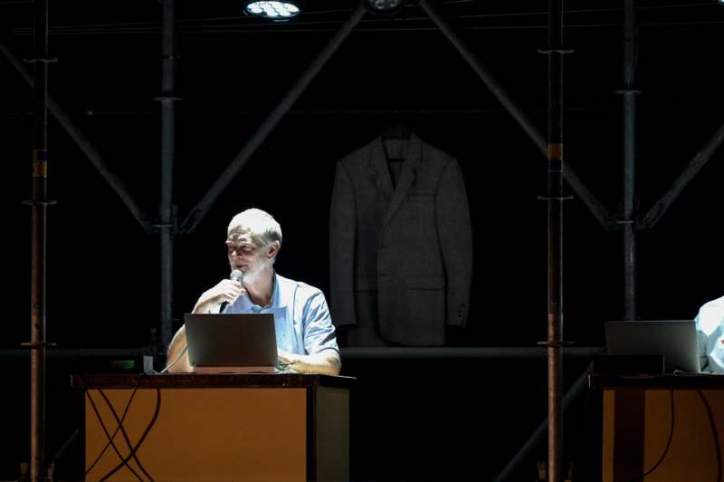 a man sitting at a podium with a microphone