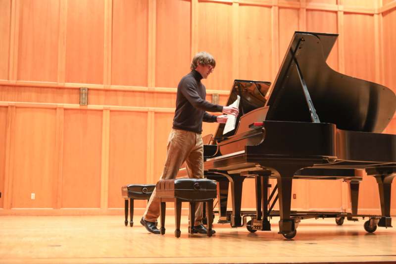 a man standing next to a piano