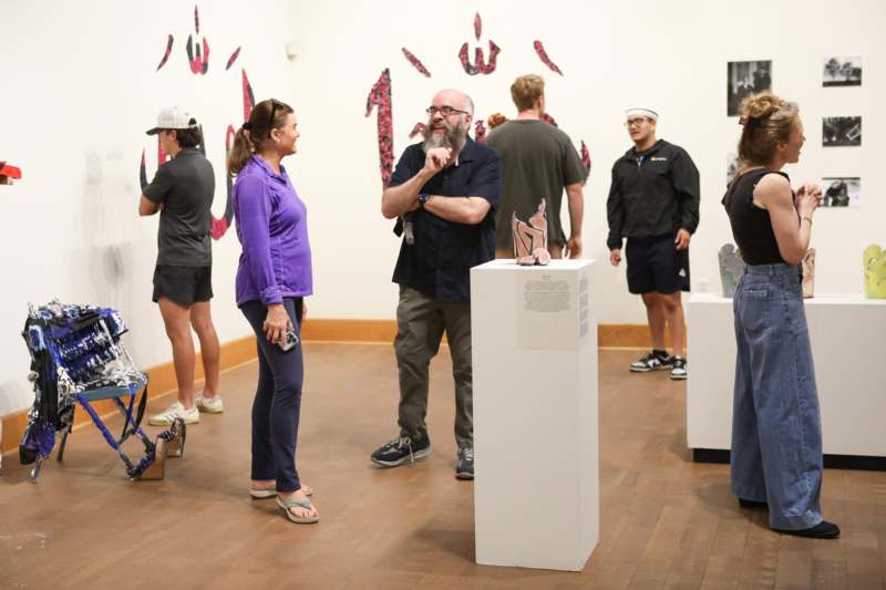 a group of people standing in a room with art on the wall