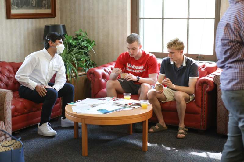 a group of men sitting on red couches in a room