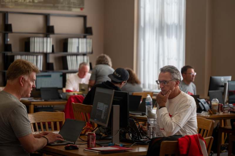 a group of people sitting at a table with computers
