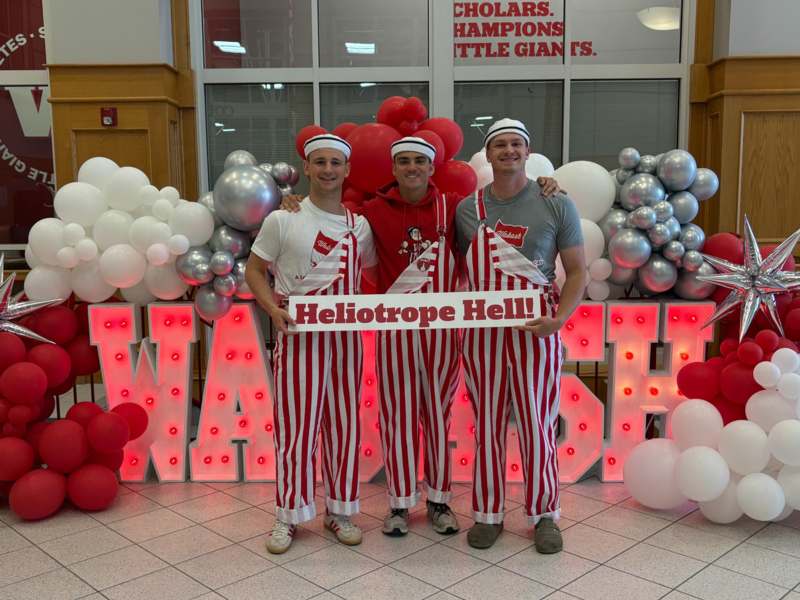 a group of men wearing striped pants and holding a sign
