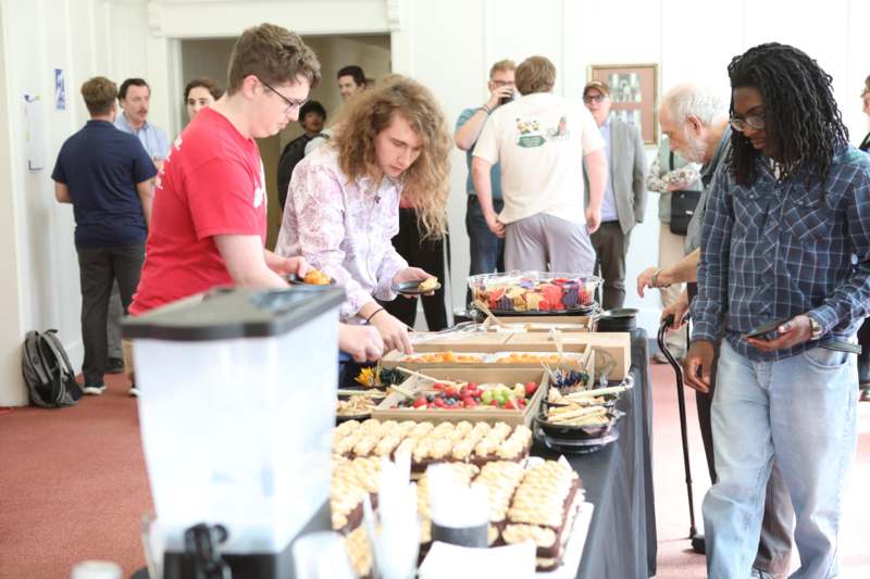 a group of people standing around a table full of food