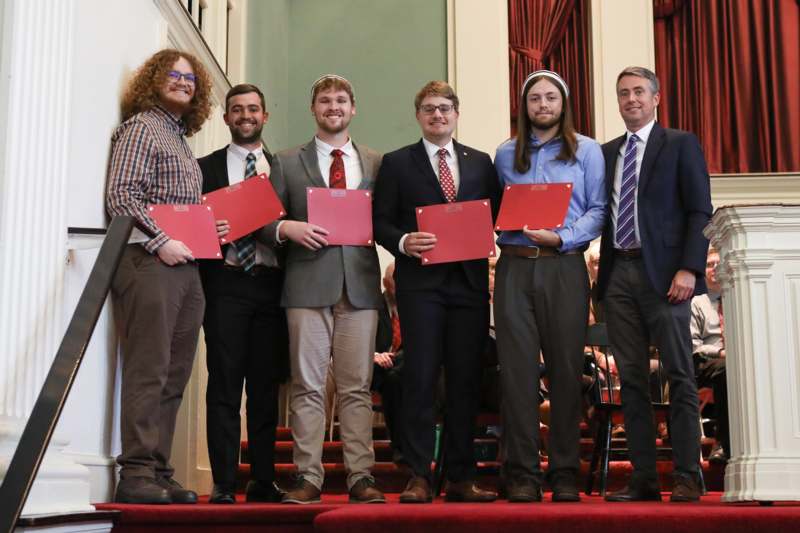 a group of men holding red folders