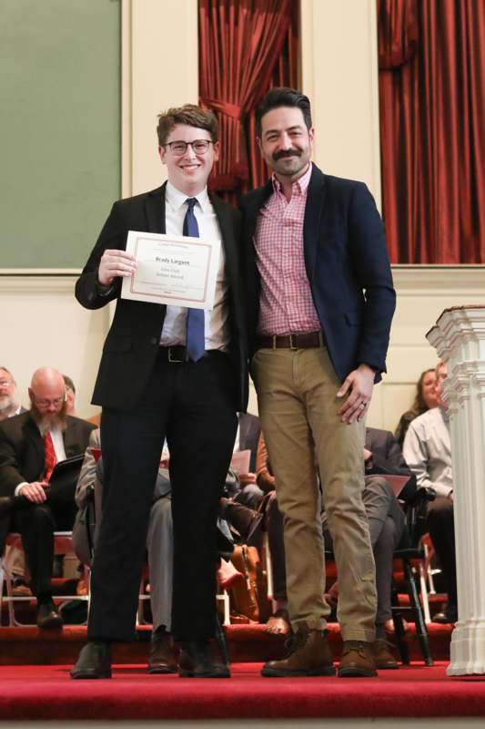 two men standing together holding a certificate