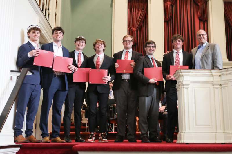 a group of men holding red folders