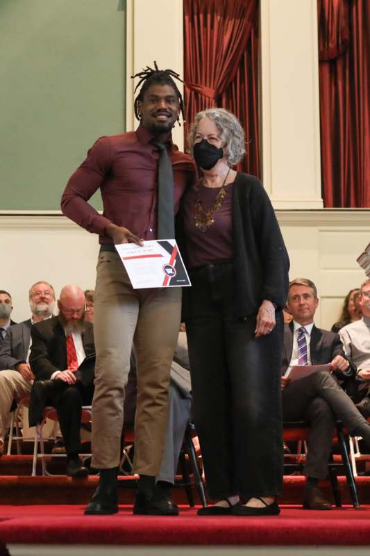 a man and woman standing on a stage with a man wearing a mask