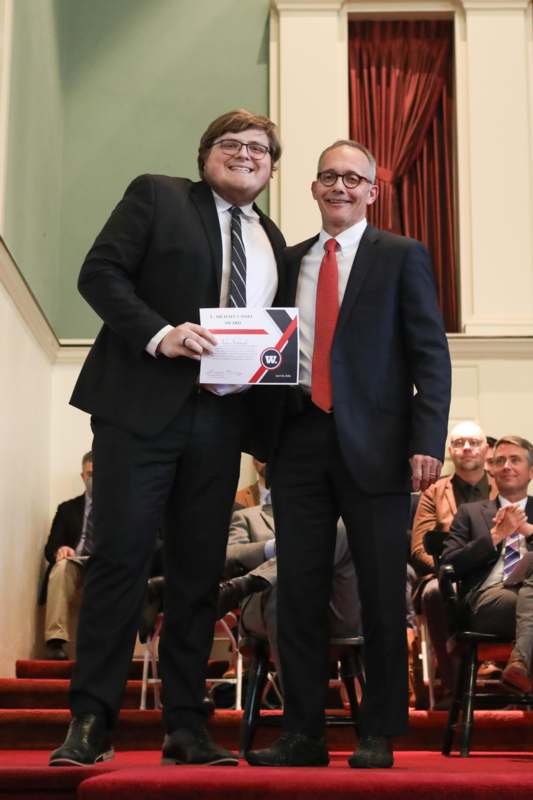 two men in suits holding a certificate
