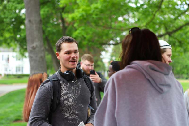 a man with headphones around his neck talking to a woman