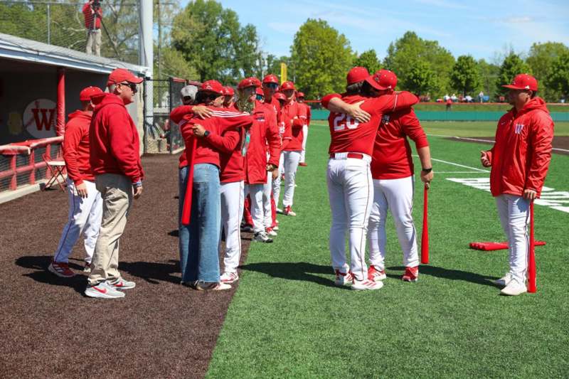 a group of people in red shirts hugging on a field