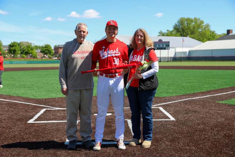a man holding a baseball bat and a woman standing on a baseball field