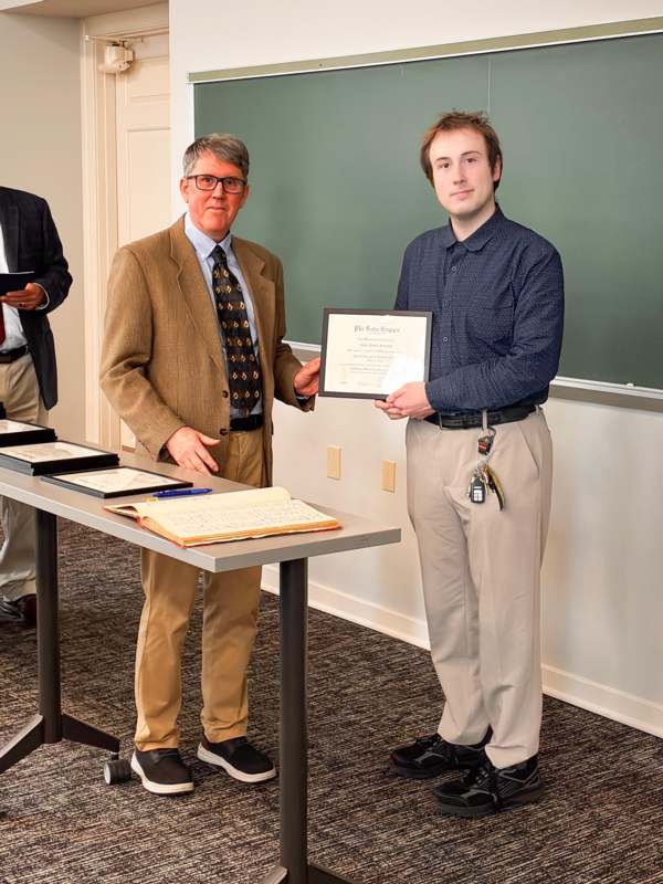 a man holding a certificate and standing next to a table