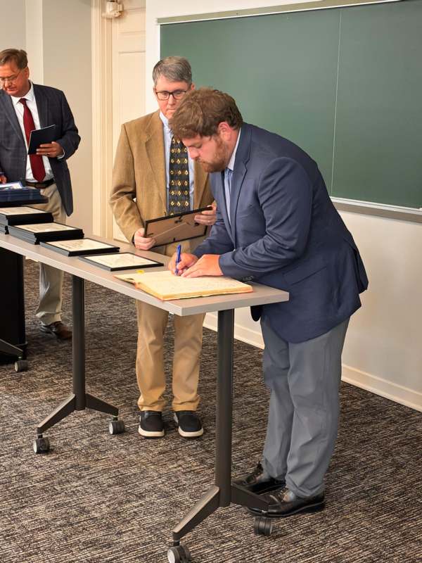 a man standing at a table signing a document