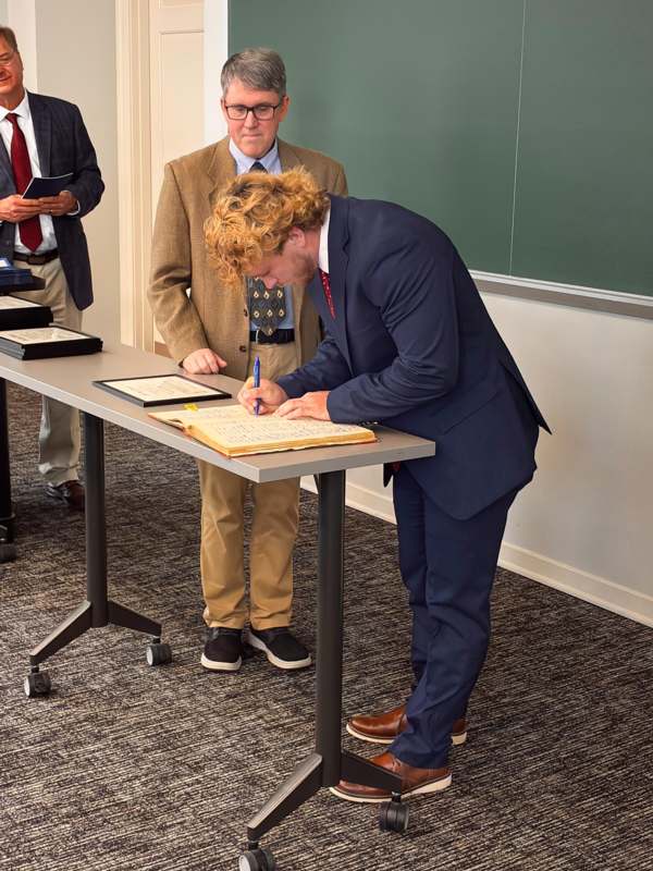 a man in a suit signing a book