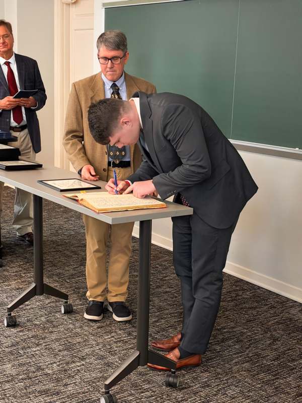 a man in a suit writing on a book