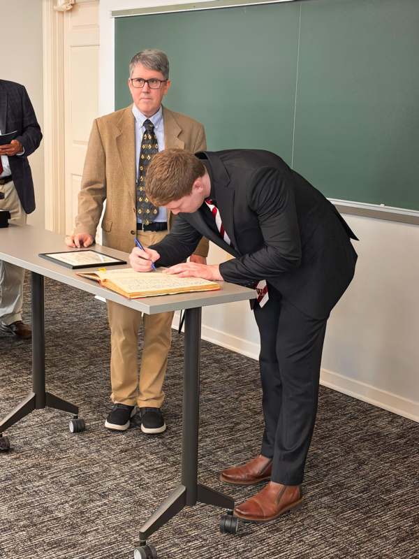 a man in a suit signing a document