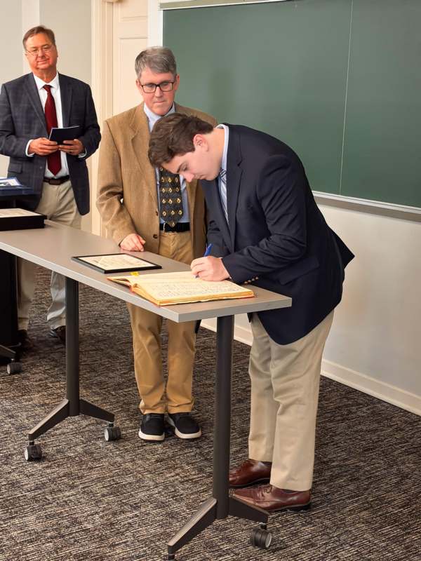 a man in a suit writing on a book