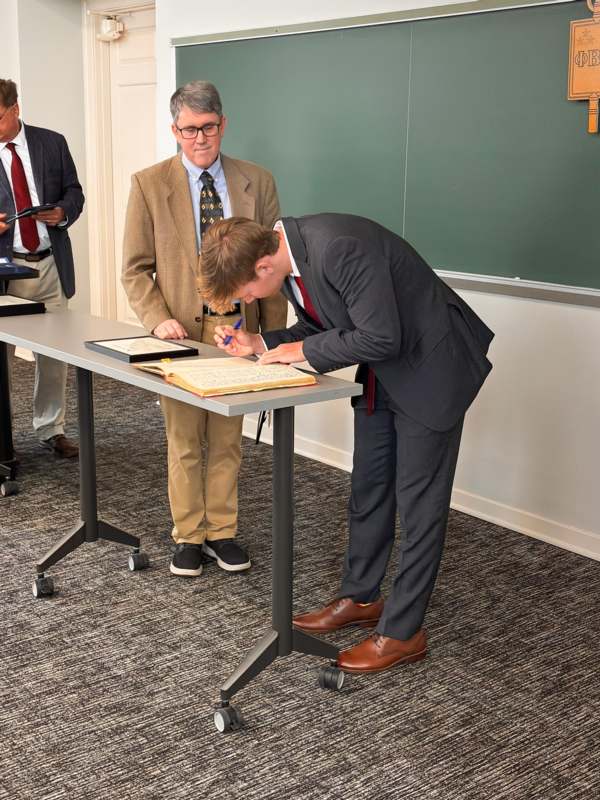 a man in a suit writing on a book