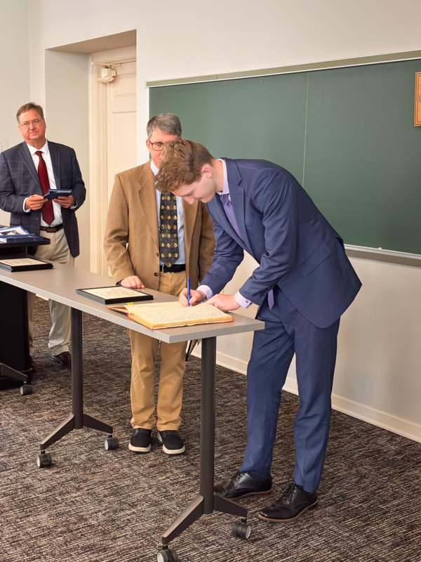 a man in a suit writing on a book