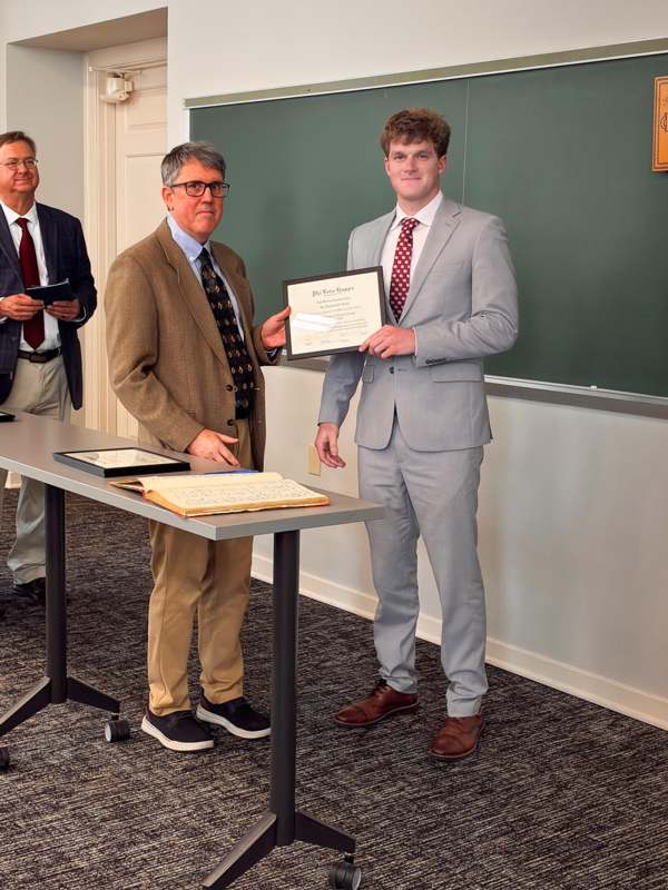 a man in a suit holding a certificate
