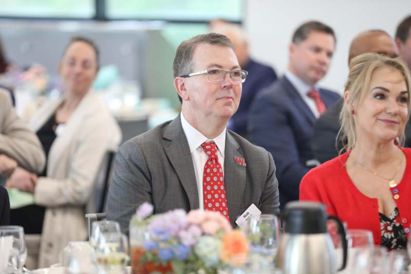a man in a suit and tie sitting at a table with other people