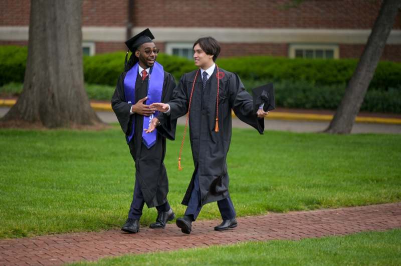 2026 Commencement Album 2 - a man in graduation gowns and cap walking on a brick path