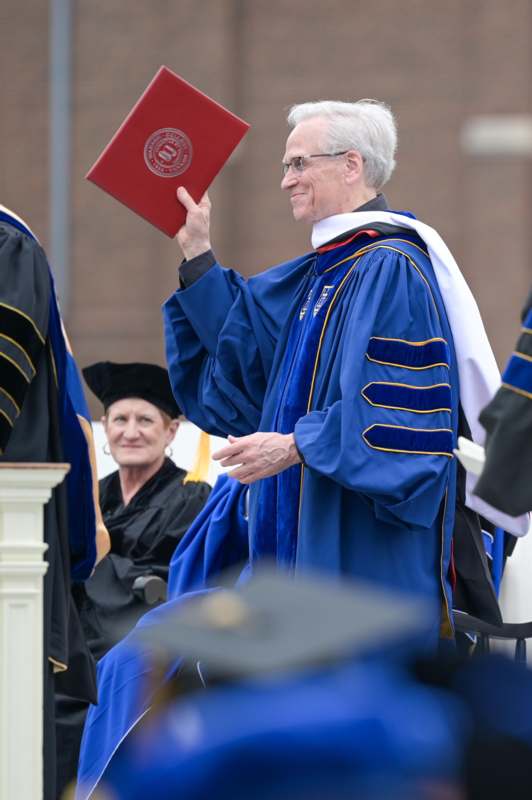 a man in a blue robe holding a red book