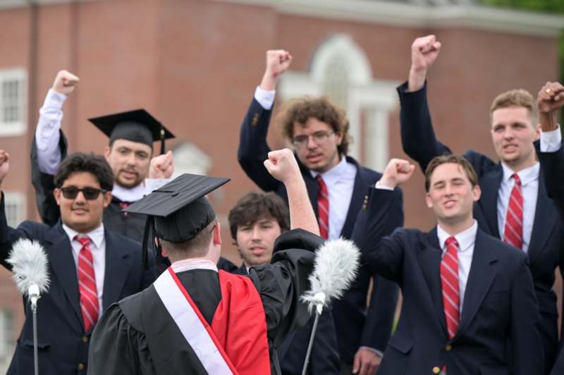 a group of people in suits and gowns raising their fists
