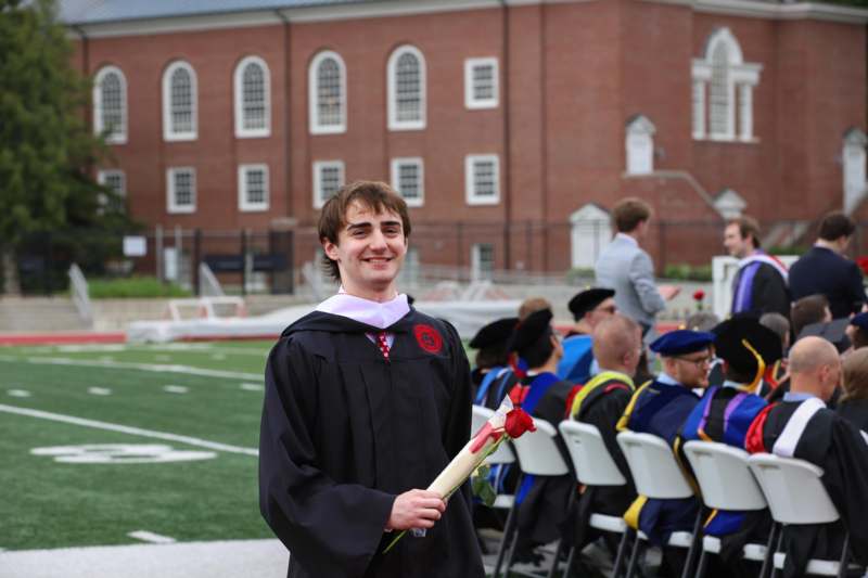 a man in a graduation gown holding a rose