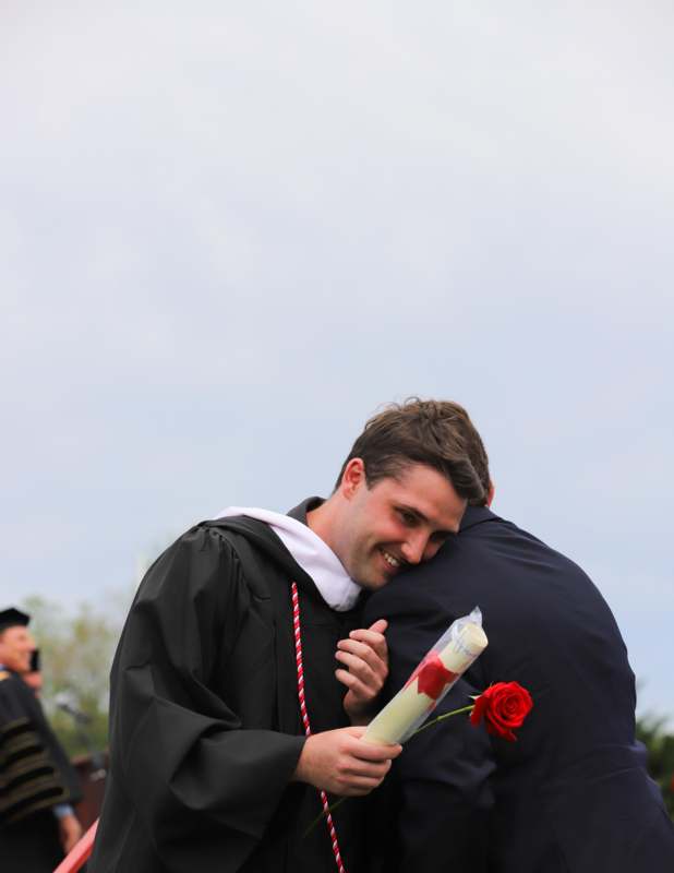 a man hugging a man with a rose