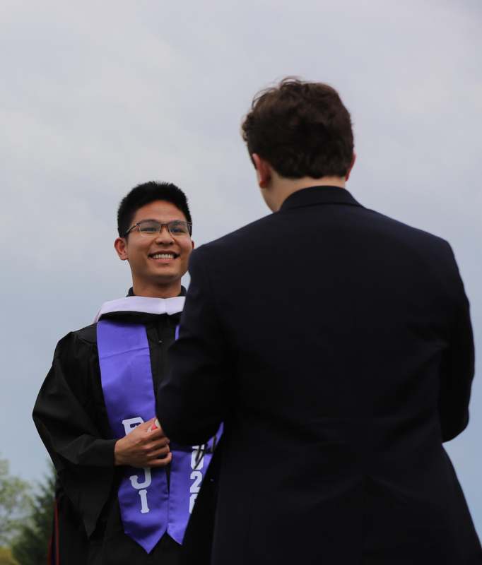 a man in a graduation gown smiling