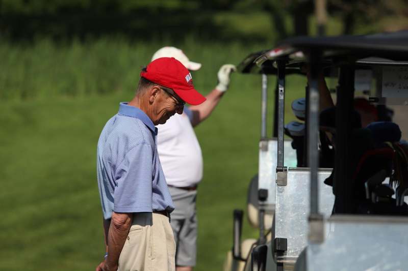 a man in a red hat standing next to a golf cart
