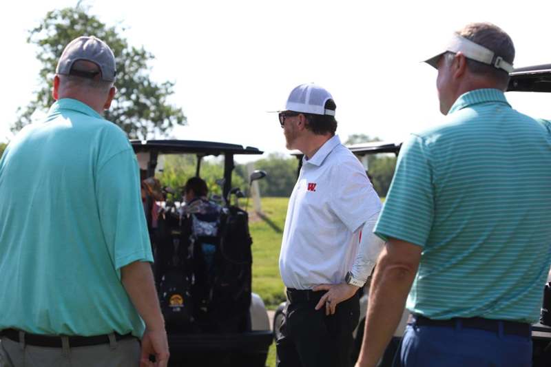a group of men standing in front of golf carts