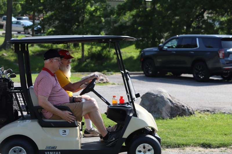 two men sitting in a golf cart