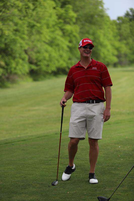 a man in a red shirt and cap holding a golf club