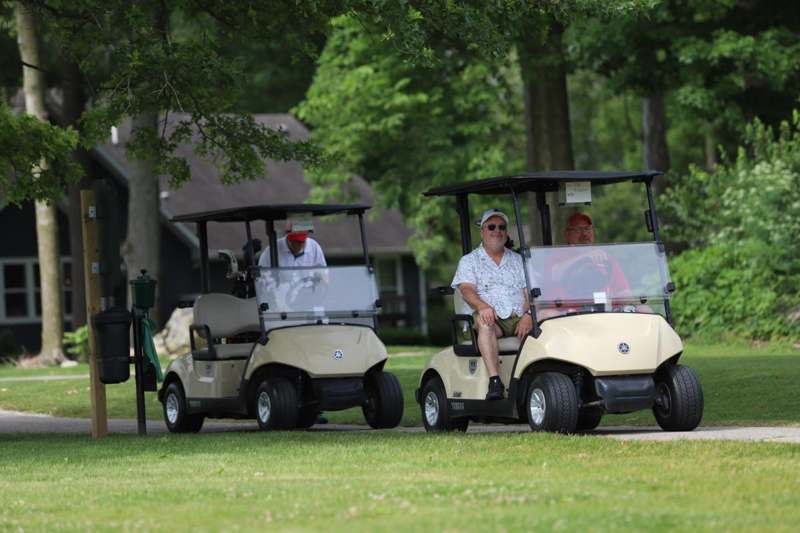 a group of men driving golf carts