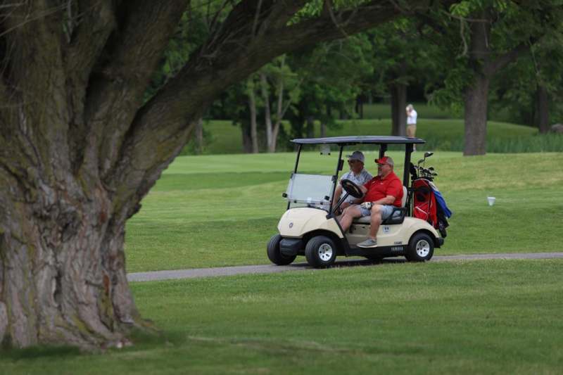 a group of men driving a golf cart