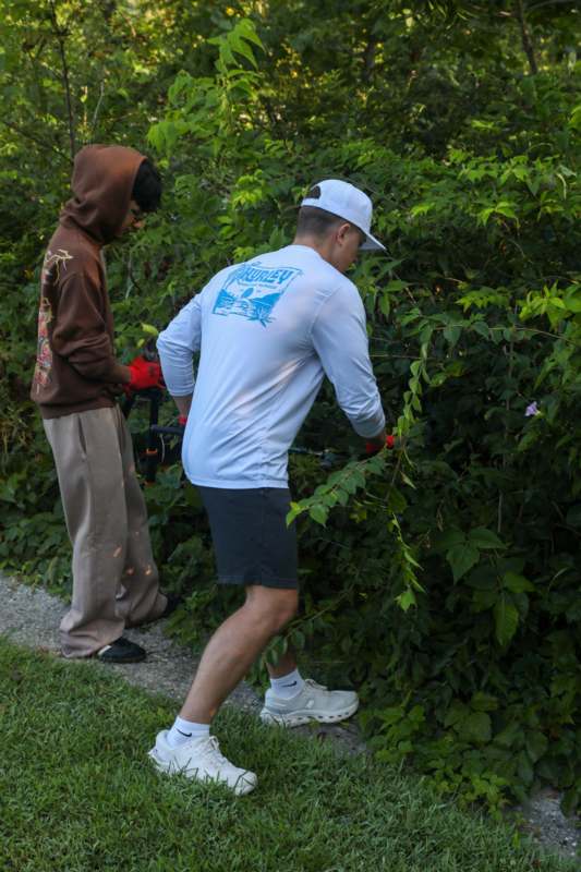 a man and woman cutting bushes