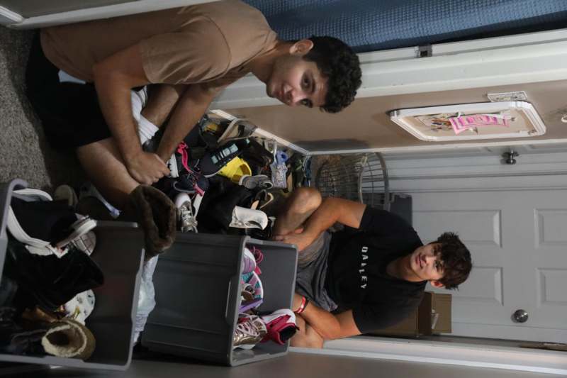two men sitting in a hallway with shoes in boxes